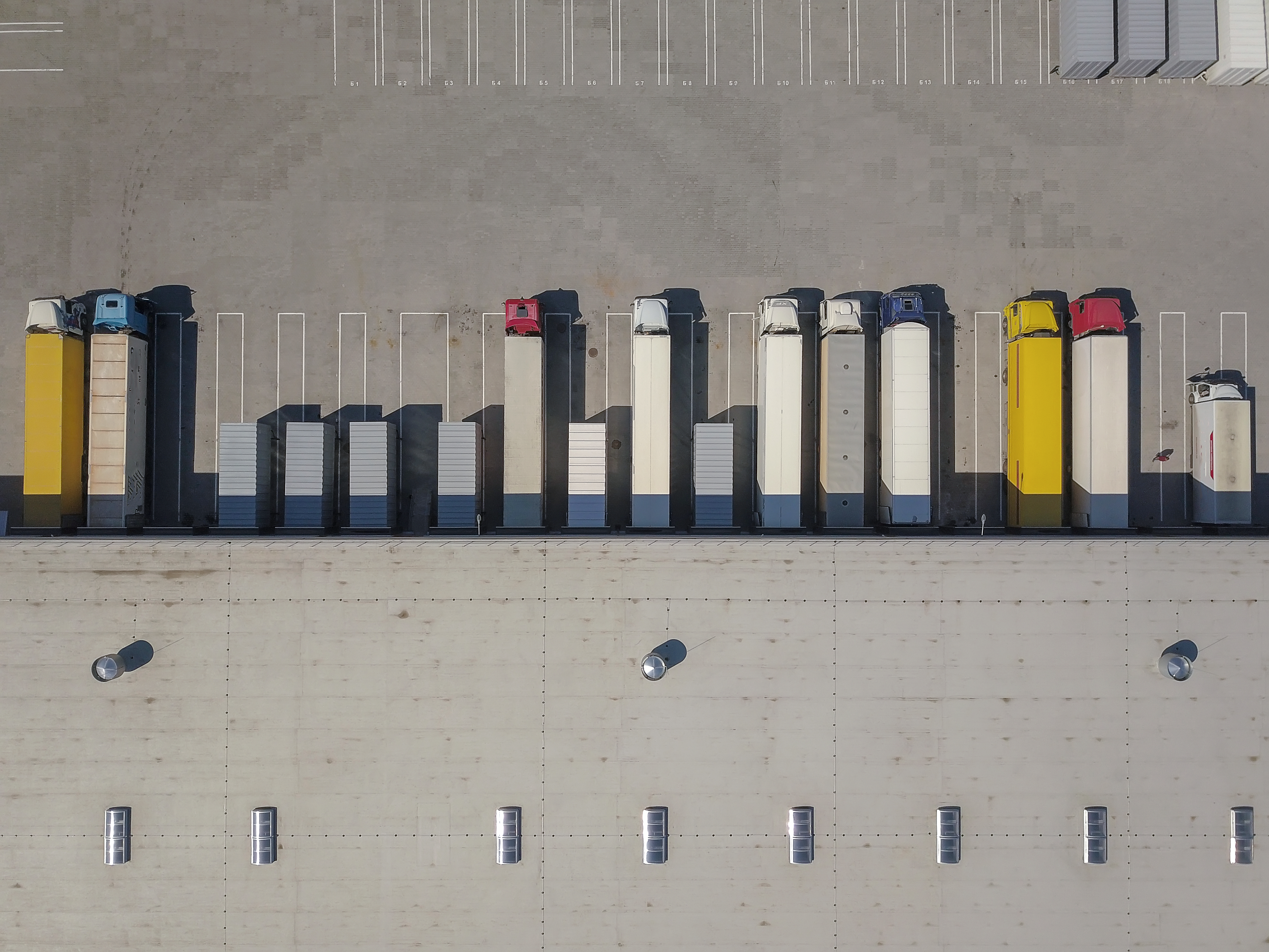 Aerial view of goods warehouse. Logistics center in industrial city zone from above. Aerial view of trucks loading at logistic center