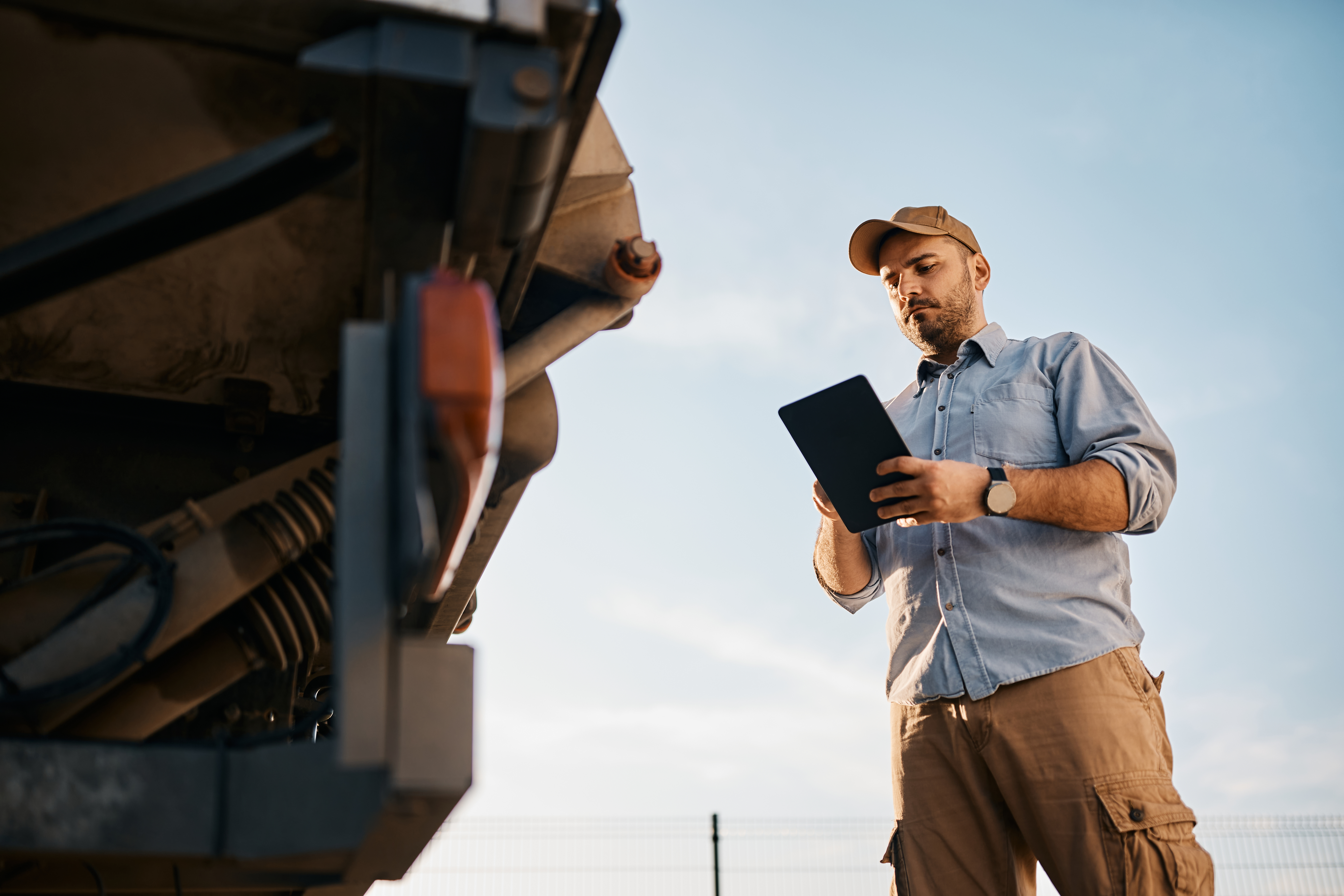 Low angle view of truck driver using digital tablet outdoors. Copy space.