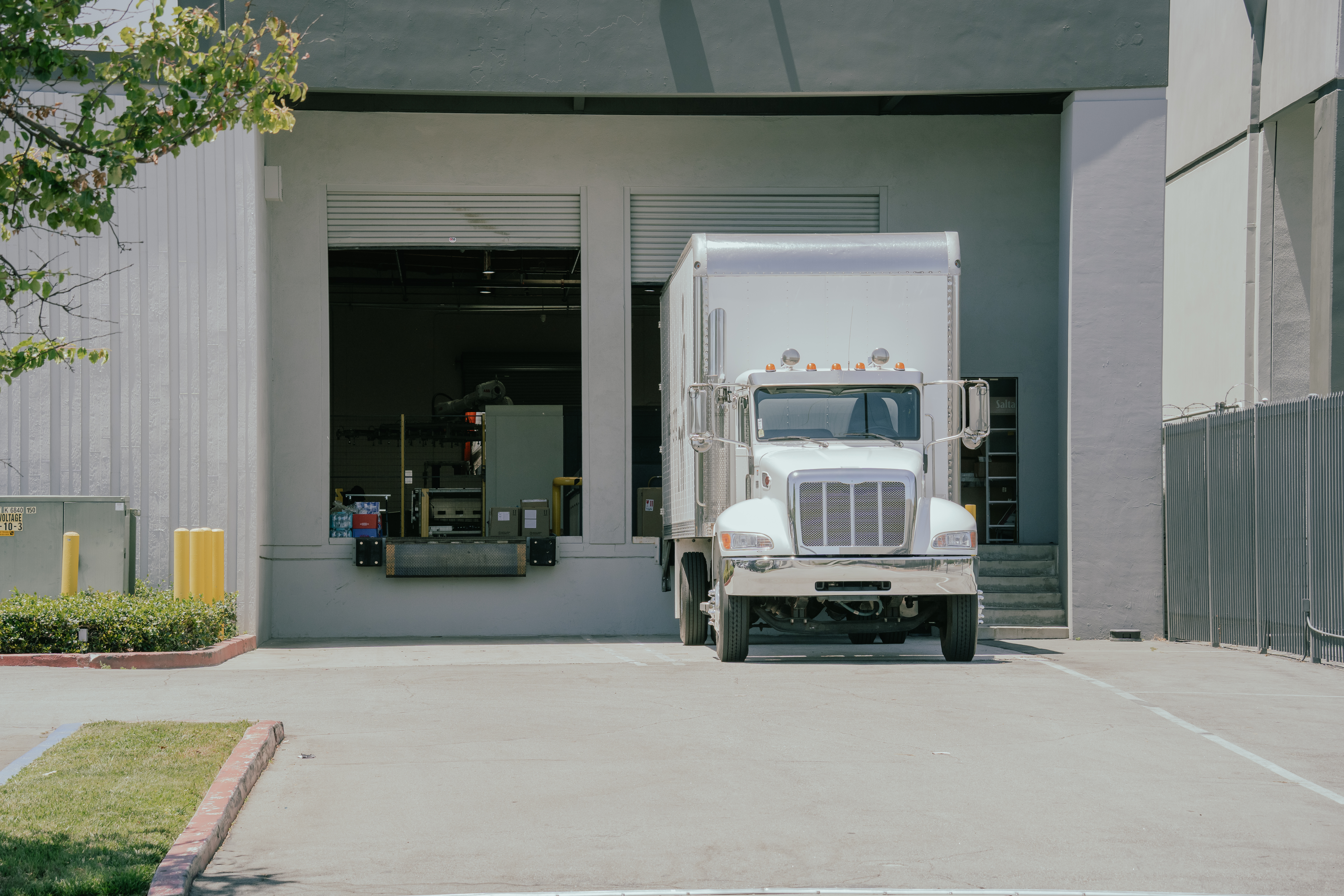 A white delivery truck sits outside a loading dock, ready for unloading and loading operations